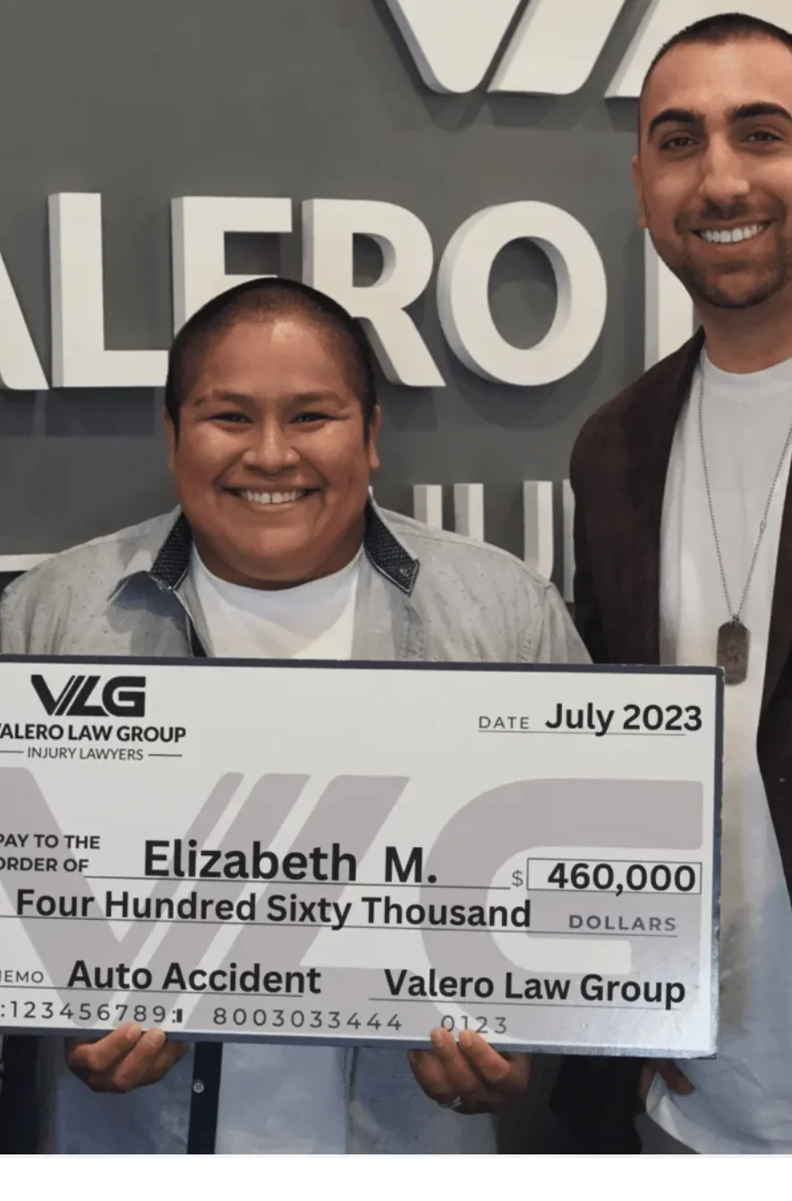 Valero Law Group client Elizabeth M. holding a $460,000 auto accident settlement check