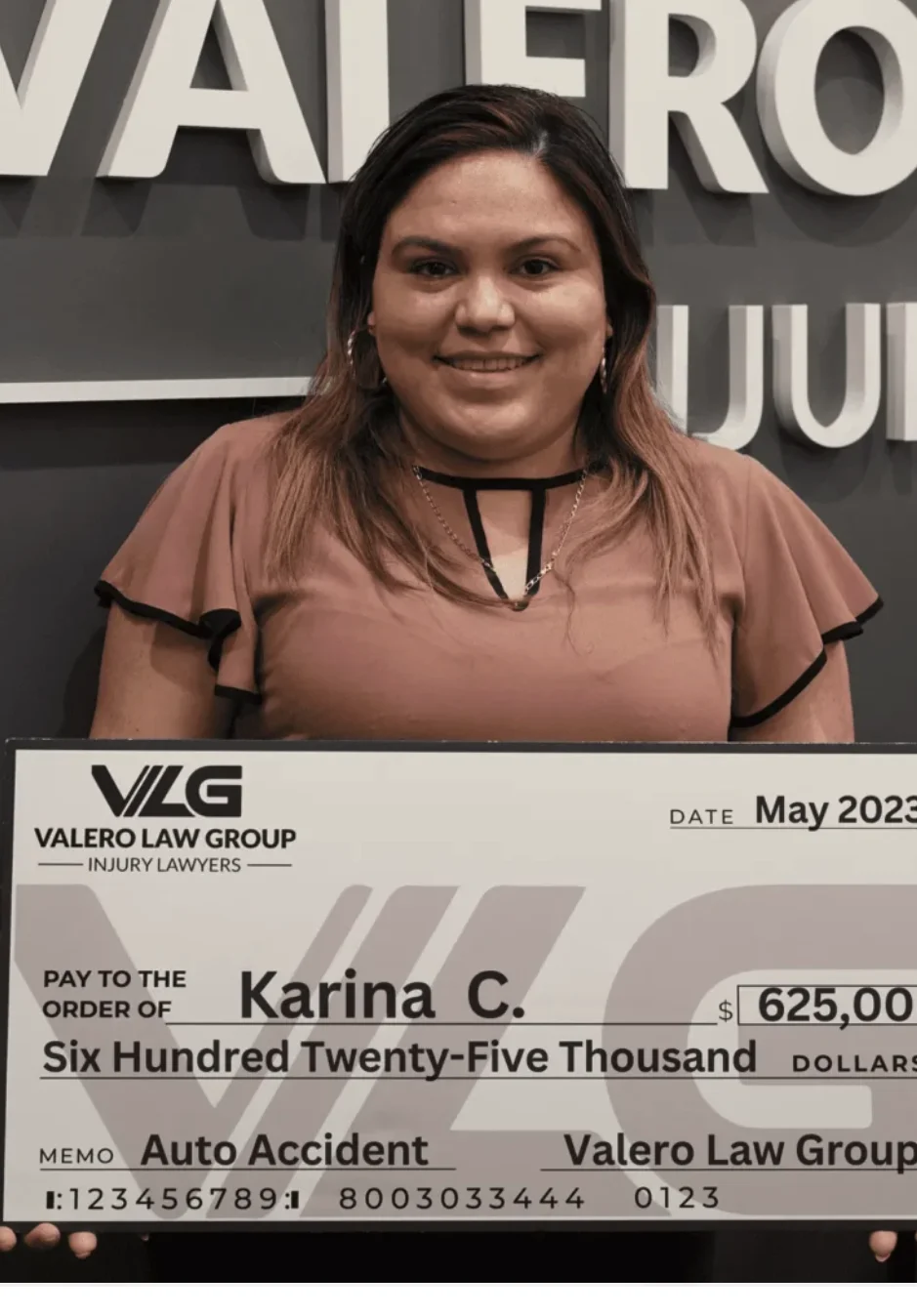 Valero Law Group client Karina C. holding a $625,000 auto accident settlement check