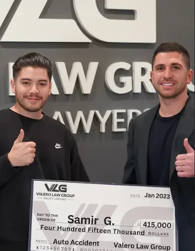 Valero Law Group client Samir G. holding a $415,000 auto accident settlement check